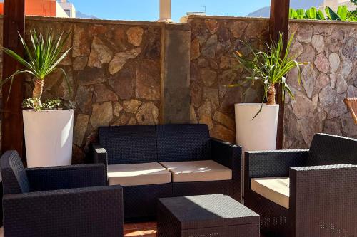 a patio with two chairs and two potted plants at Hotel La Aldea Suites in La Aldea de San Nicolas