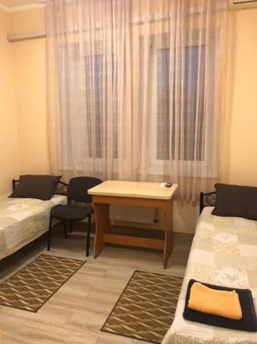 a room with two beds and a table and a window at Karavella in Mykolaiv