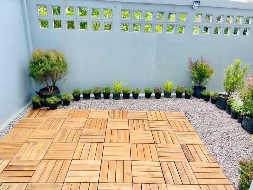 a patio with a wooden floor and potted plants at Lamoon Trang in Ban Phlu Phli