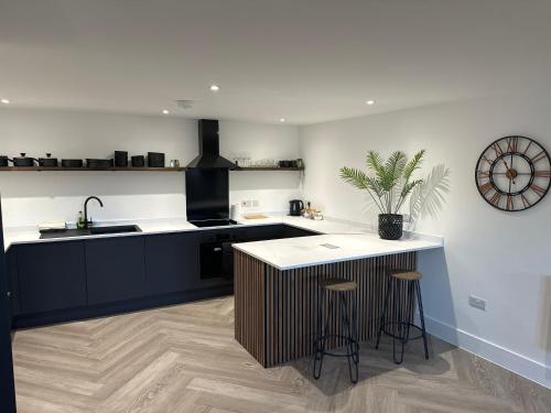 a kitchen with a sink and a counter with stools at New 2 Bed Apartment in Royston High St in Royston