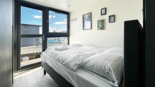 a bedroom with a bed and a large window at Golfzicht by Droomvilla in Uitgeest