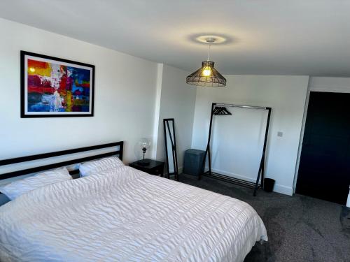 a bedroom with a bed and a painting on the wall at New 2 Bed Apartment in Royston High St in Royston