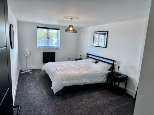 a white bedroom with a bed and two windows at New 2 Bed Apartment in Royston High St in Royston