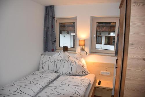 a small bedroom with a bed and two windows at Landhaus Anneliese in Going
