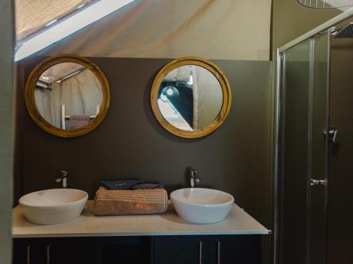 a bathroom with two sinks and two mirrors at Longhill Reserve in Addo