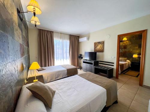 a hotel room with two beds and a television at Hotel La Aldea Suites in La Aldea de San Nicolas