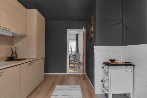 cocina con paredes negras, armarios de madera y mesa en Leilighet i Tromsdalen med en fantastisk utsikt over Tromsø Sentrum, en Trondalen