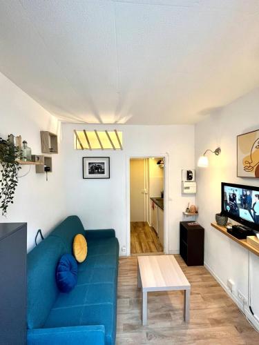 un salon avec un canapé bleu et une table dans l'établissement Appartement Studio cosy 17ème, à Paris