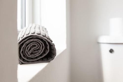 a rolled up towel sitting on a window sill next to a toilet at Modern 5-Bedroom House with 8 Beds, Perfect for Contractors, Extended Stay Savings in Wallasey