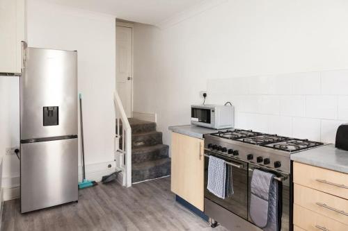 a kitchen with a stove and a refrigerator at Modern 5-Bedroom House with 8 Beds, Perfect for Contractors, Extended Stay Savings in Wallasey