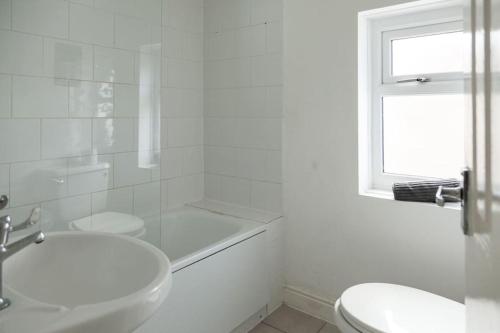 a white bathroom with a sink and a toilet at Modern 5-Bedroom House with 8 Beds, Perfect for Contractors, Extended Stay Savings in Wallasey