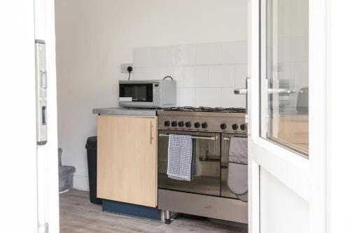 a kitchen with a stove and a microwave at Modern 5-Bedroom House with 8 Beds, Perfect for Contractors, Extended Stay Savings in Wallasey