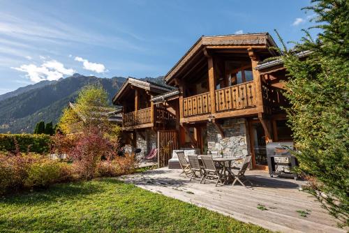 une cabane en rondins avec une table et des chaises sur une terrasse dans l'établissement Chalet Kaiya - Alpes Travel - Les Praz - sleeps 8, à Chamonix-Mont-Blanc
