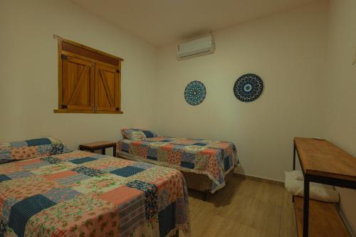 Zimmer mit 2 Betten, einem Fenster und einem Tisch in der Unterkunft Chalés Samambaia 1 in Bananeiras