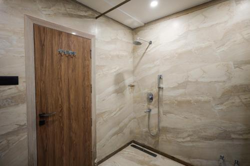 a bathroom with a shower with a wooden door at Myestay Elite The Ultimate Luxury Spacious Villa in Varanasi