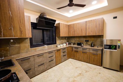a large kitchen with wooden cabinets and a ceiling fan at Myestay Elite The Ultimate Luxury Spacious Villa in Varanasi