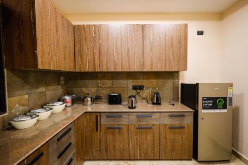 a kitchen with wooden cabinets and a refrigerator at Myestay Elite The Ultimate Luxury Spacious Villa in Varanasi
