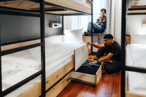 a man sitting on the floor in a room with bunk beds at Urban House Copenhagen by MEININGER in Copenhagen