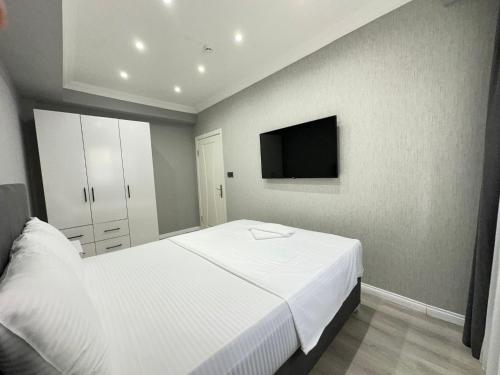 a bedroom with a white bed and a flat screen tv at Casa Florya Travel Apartments in Istanbul