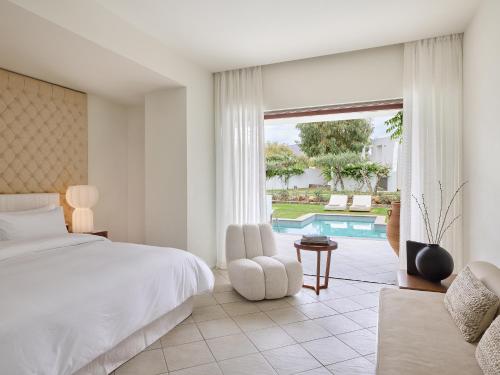 a bedroom with a bed and a chair and a pool at Amirandes, A Grecotel Resort to Live in Gouves