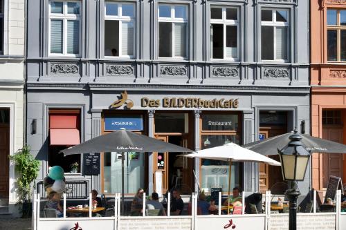a restaurant with tables and umbrellas in front of a building at Das BilderbuchCafe - Ferien - Apartment NO 3 - Markt 7 in Havelberg