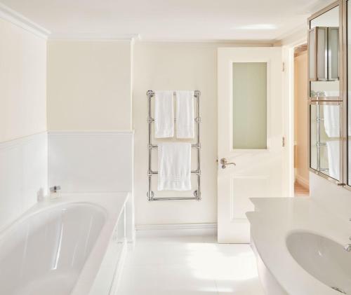 a white bathroom with two sinks and a tub at The Connaught, Maybourne in London