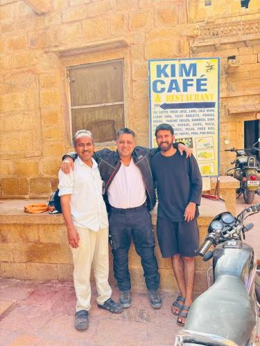 a group of three people standing in front of a building at Marigold Home Stay in Jaisalmer