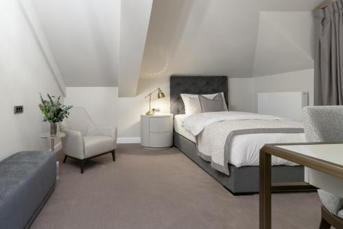 a white bedroom with a bed and a chair at Reea Boutique Hotel in Târgovişte