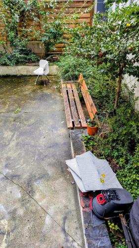 un banc en bois assis dans une cour à côté d'une pelouse dans l'établissement Studio Paris, ground floor, à Asnières-sur-Seine