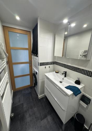 une salle de bain blanche avec un lavabo et un miroir dans l'établissement La maison cozy, à Le Soler