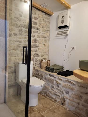 La salle de bains est pourvue de toilettes et d'un mur en pierre. dans l'établissement La grange, à Aspères