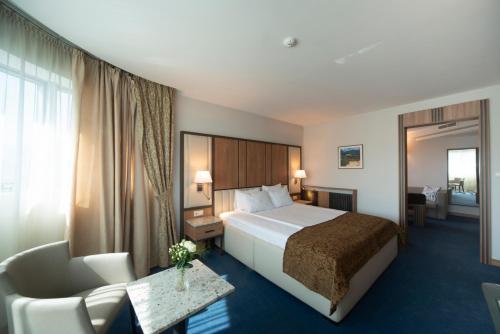 a hotel room with a large bed and a chair at Legends Hotel in Sofia