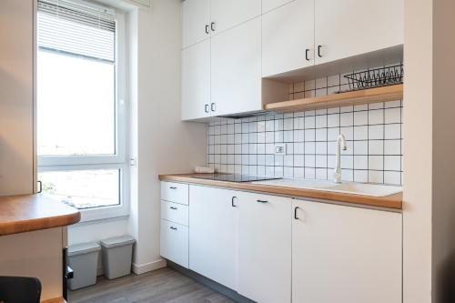 a kitchen with white cabinets and a window at Moderno bilocale sui Navigli - Mirable PM in Milan