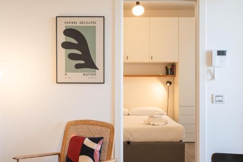 a room with a bed and a chair with a picture on the wall at Moderno bilocale sui Navigli - Mirable PM in Milan