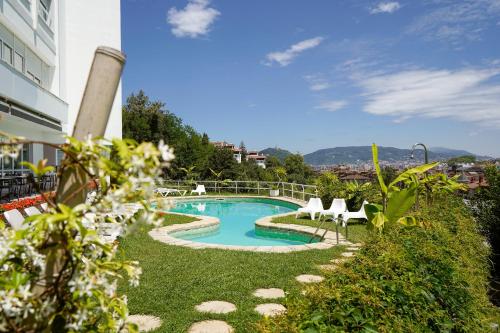 a swimming pool with two chairs and a building at Hotel Avenida in Donostia-San Sebastián