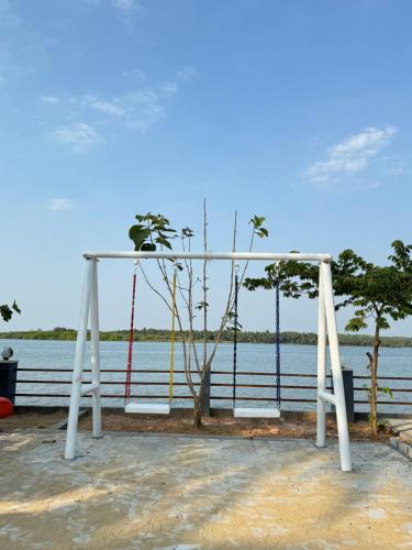 a swing set in front of the water at THE BACKWATER HOMESTAYy in Kalyānpur