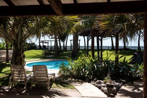 two chairs and a swimming pool with palm trees at Monterrico Resort in La Candelaria