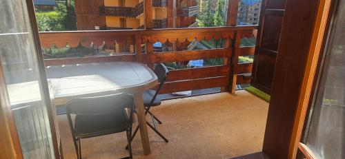 Elle comprend un balcon avec un bureau, une table et des chaises. dans l'établissement Appartement skis aux pieds BETELGEUSE, à Risoul