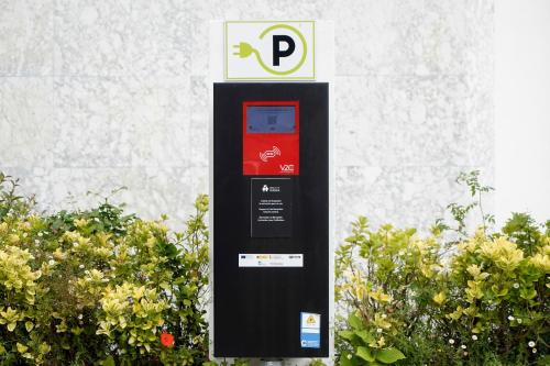 a red and black parking meter next to some bushes at Hotel Avenida in Donostia-San Sebastián