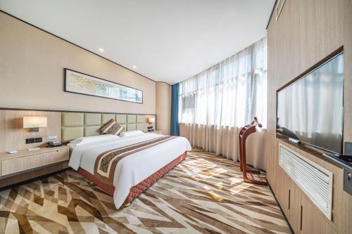 a bedroom with a large bed and a flat screen tv at Days Hotel Suzhou in Suzhou