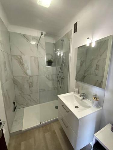 une salle de bain blanche avec une douche et un lavabo dans l'établissement Studio terrasse Saint Cyr sur Mer Les Lecques, à Saint-Cyr-sur-Mer