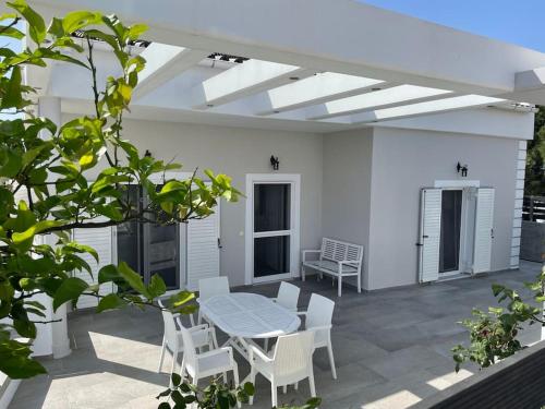 a patio with a table and white chairs and a table and a table at Villa Evanthia in Áyios Yeóryios