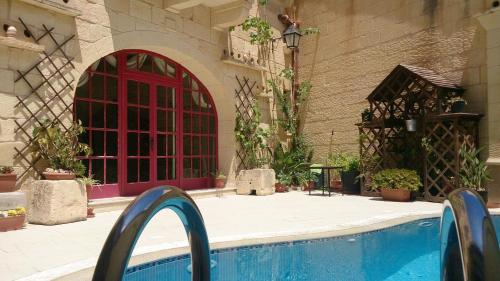 a swimming pool in a building with a red door at 3 Bedroom Holiday Farmhouse with Private Pool in Gozo in Żebbuġ