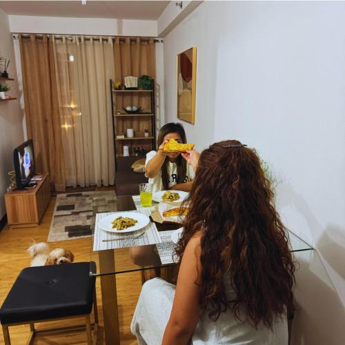 a woman sitting at a table eating a slice of pizza at Adrian's Pod Condo Rental in Davao City