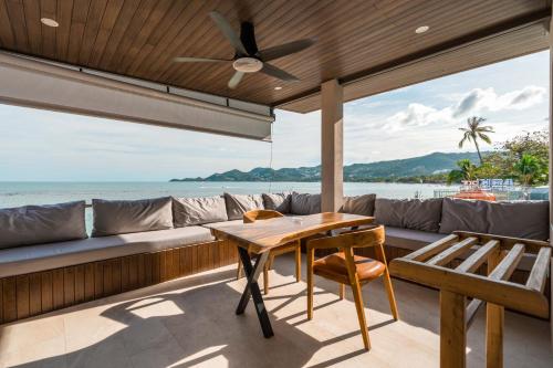 a patio with a table and a couch and the ocean at LOVE beach club Koh Samui in Chaweng