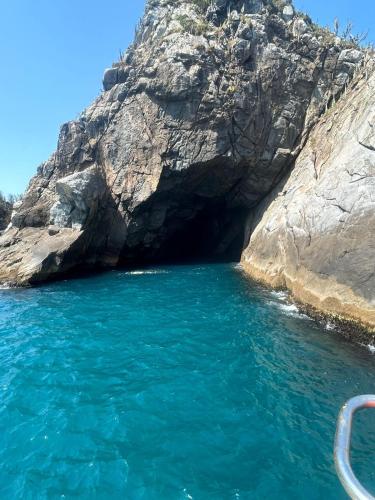 un barco frente a una cueva en el agua en Suítes Mirantes Das Baleias, en Arraial do Cabo