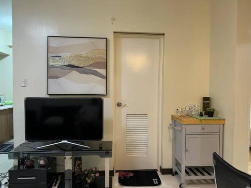a living room with a flat screen tv next to a door at Zinnia North Tower 3202 in Manila