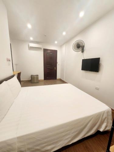 a large white bed in a room with a flat screen tv at Lakeside House Hanoi in Hanoi