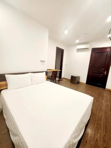 a large white bed in a room with a wooden floor at Lakeside House Hanoi in Hanoi