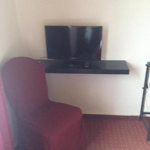 a room with a chair and a television on a table at Hotel Saarland Lebach in Lebach